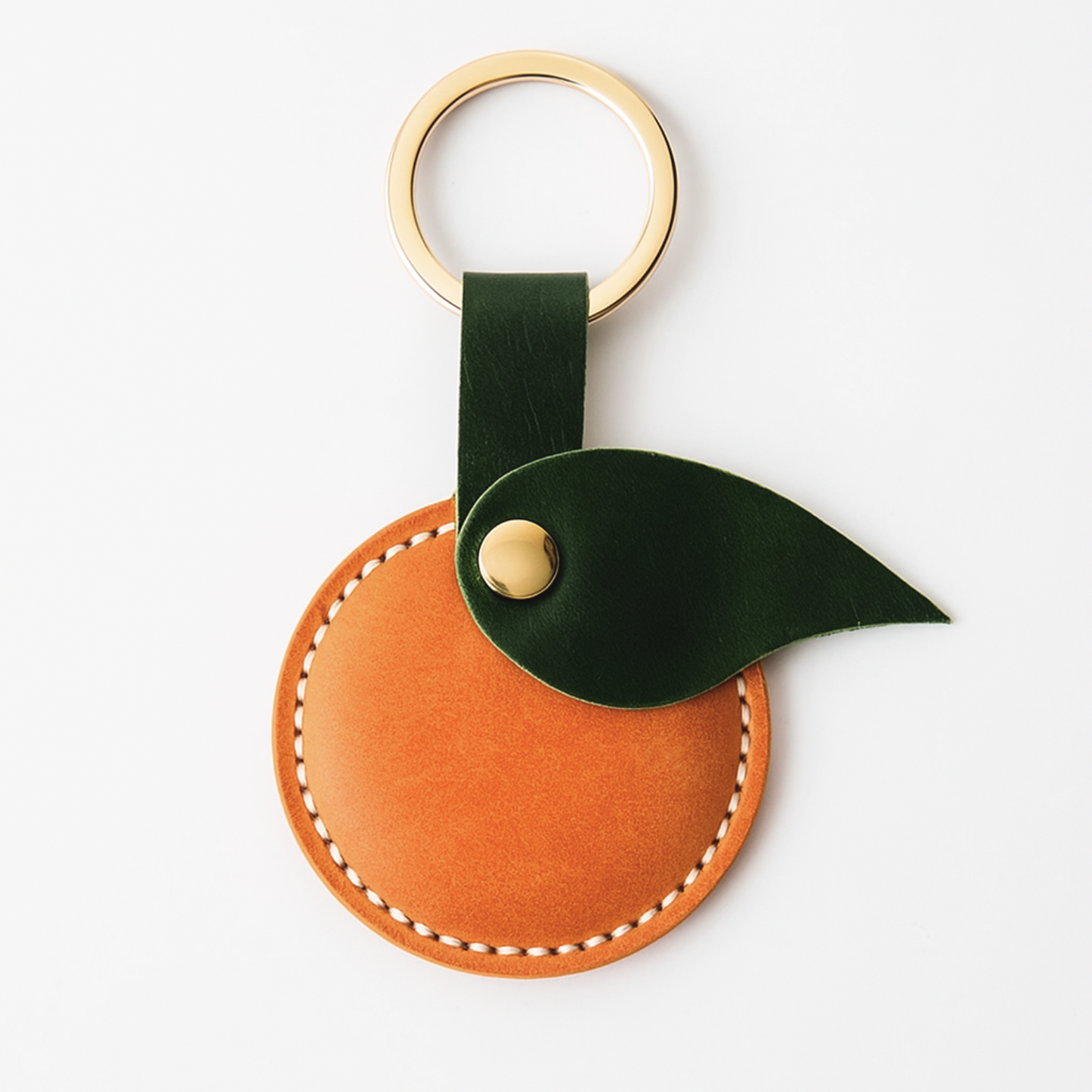 Leather orange keychain with green leaf and gold accent on a white background