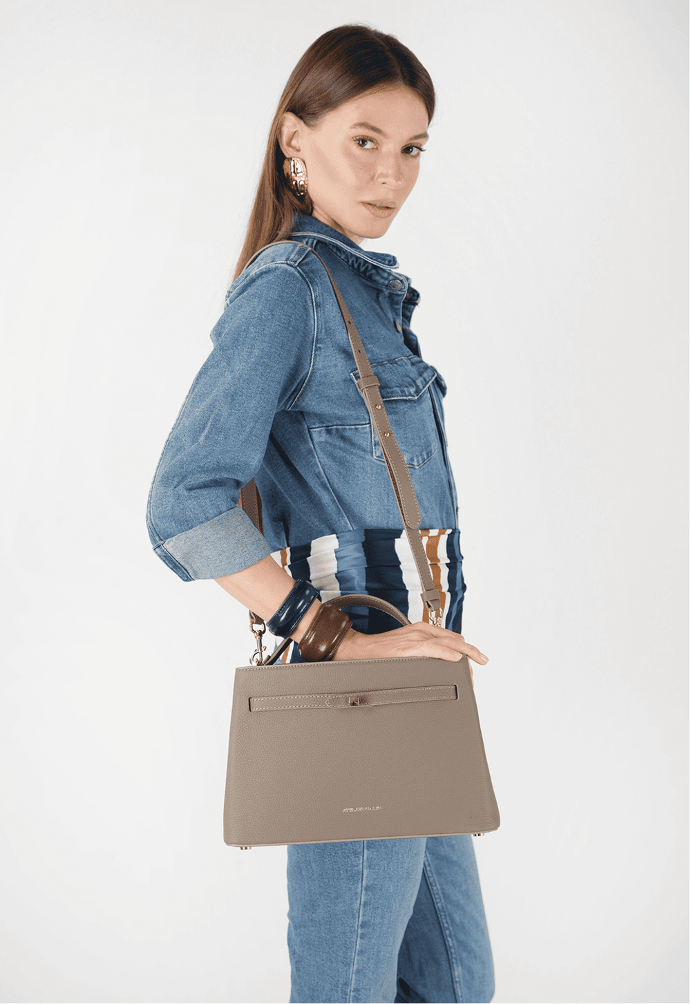 Woman holding a beige handbag against a white background