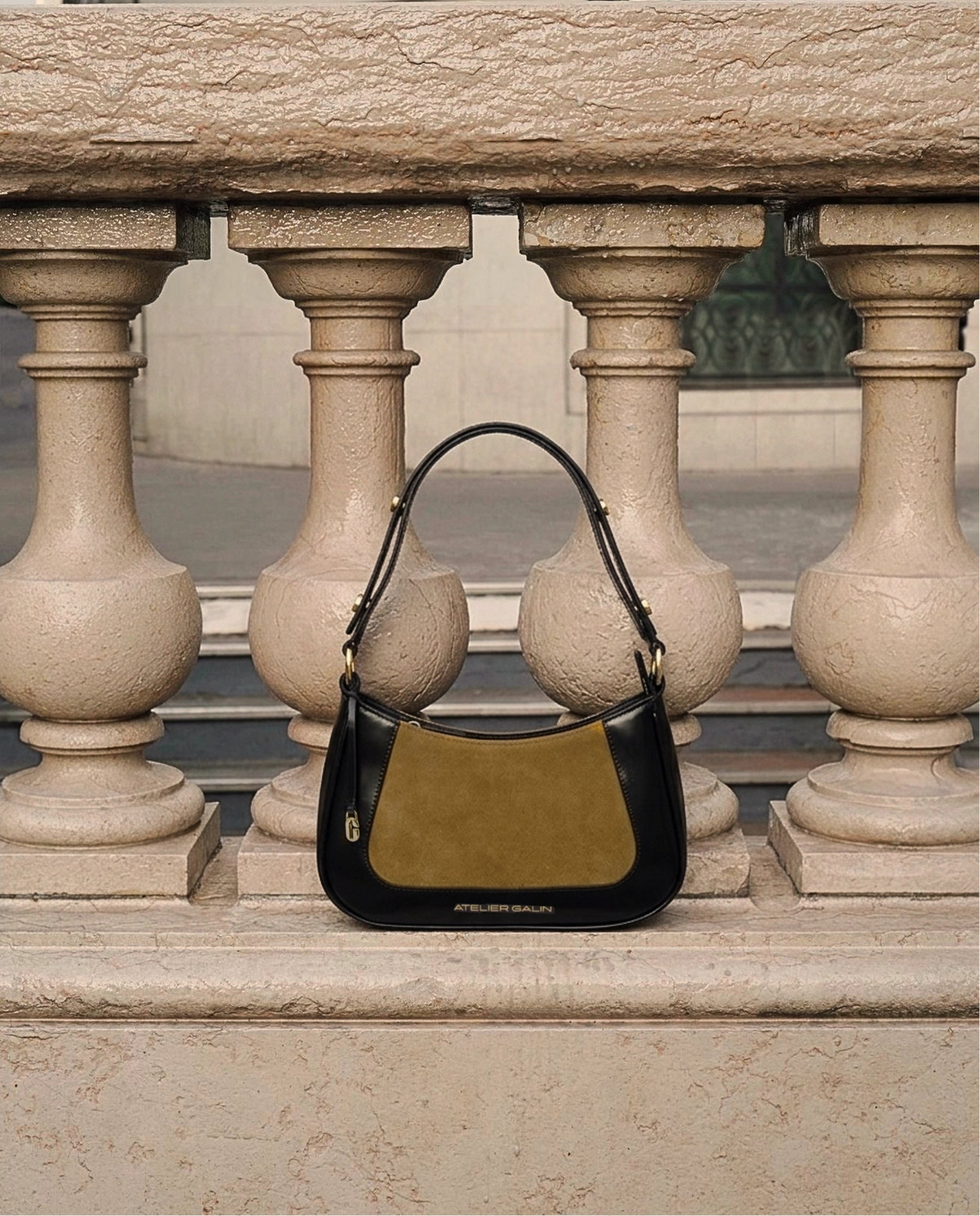 Two-tone atelier galin jasmine hobo handbag on a stone surface with architectural background