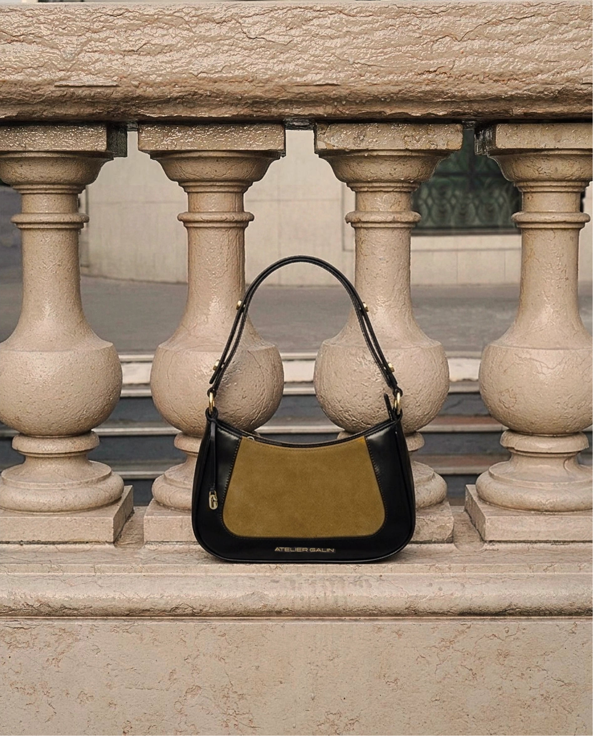 Two-tone atelier galin jasmine hobo handbag on a stone surface with architectural background
