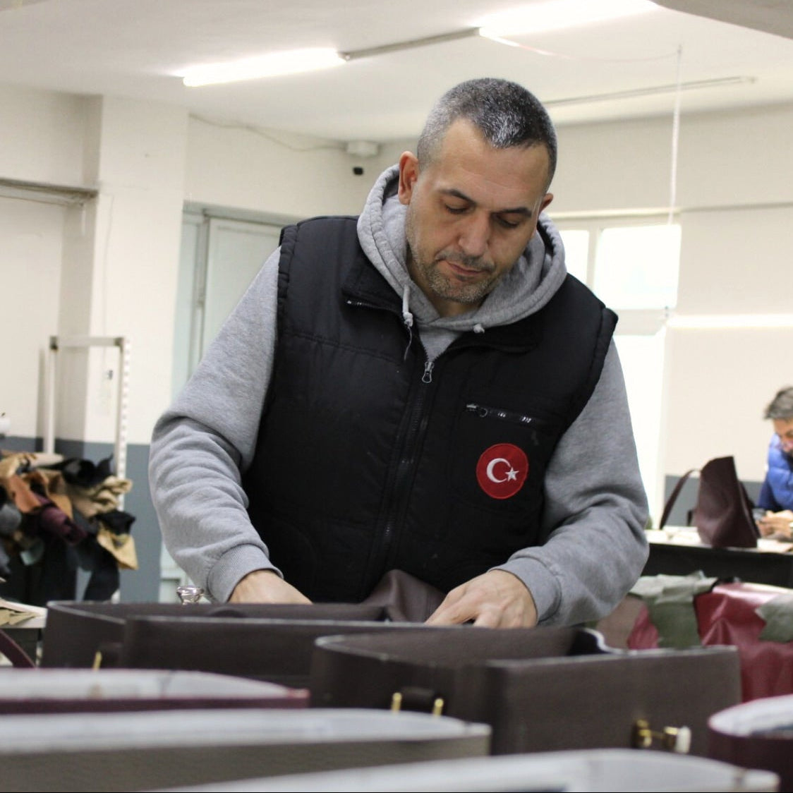 Man working in a leather bag atelier with equipment and materials around