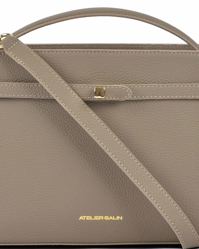 Beige atelier galin cube lock handbag with a shoulder strap on a white background