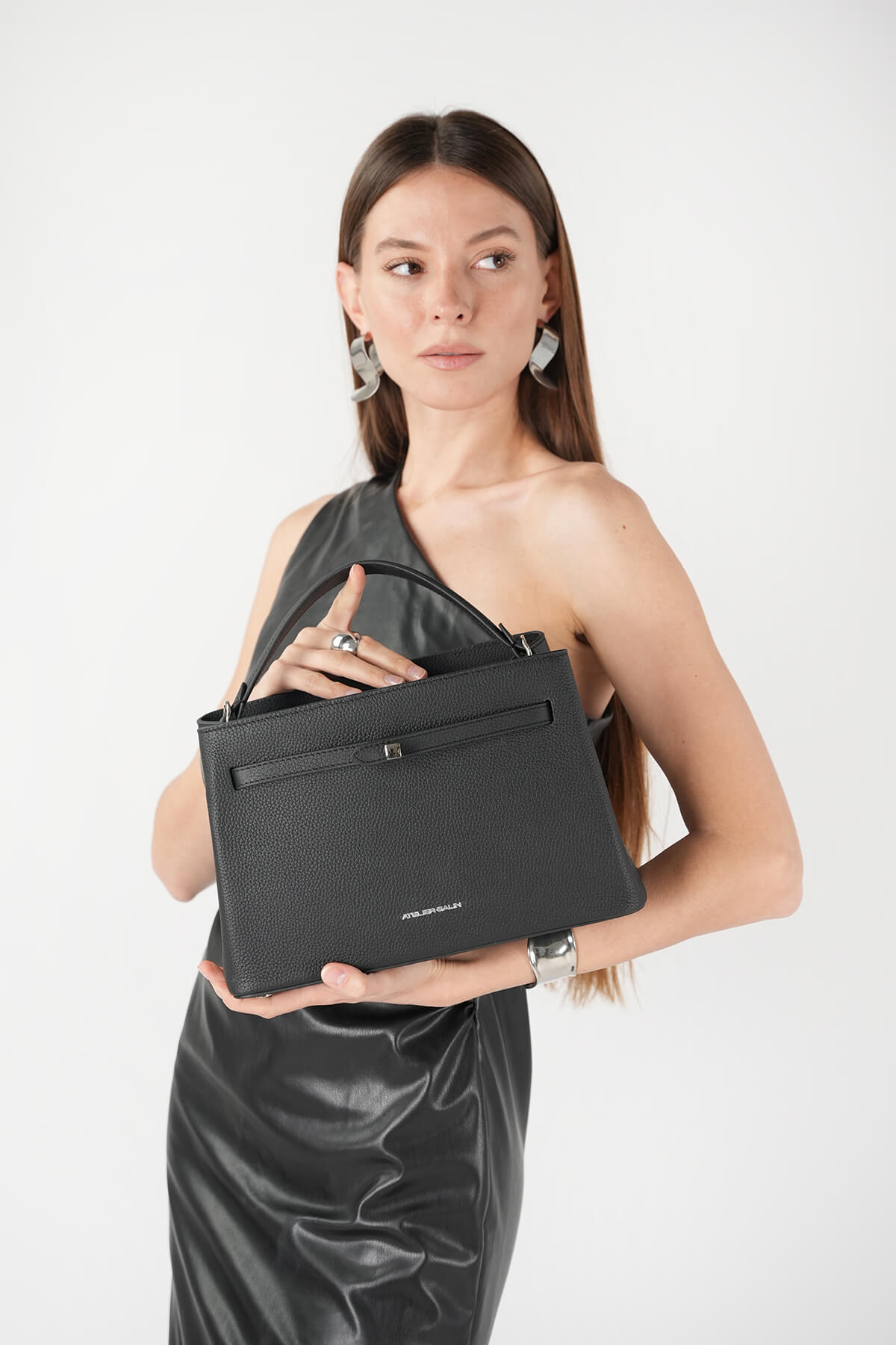 Model holding Atelier Galin Cube Lock bag in black with silver hardware 