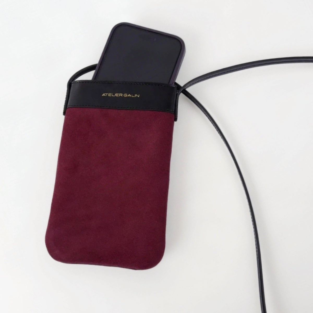 suede leather mini phone bag with an iphone inside.