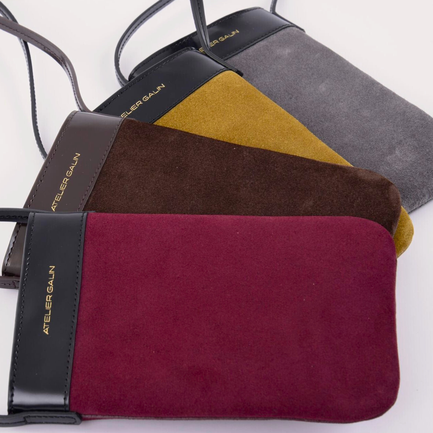 Four different burgundy, gray, ochre, brown suede mini phone bags with 'Atelier Galin' brand 